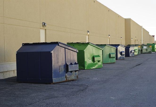 tilted front-load dumpsters being emptied by waste management workers in Bennington VT